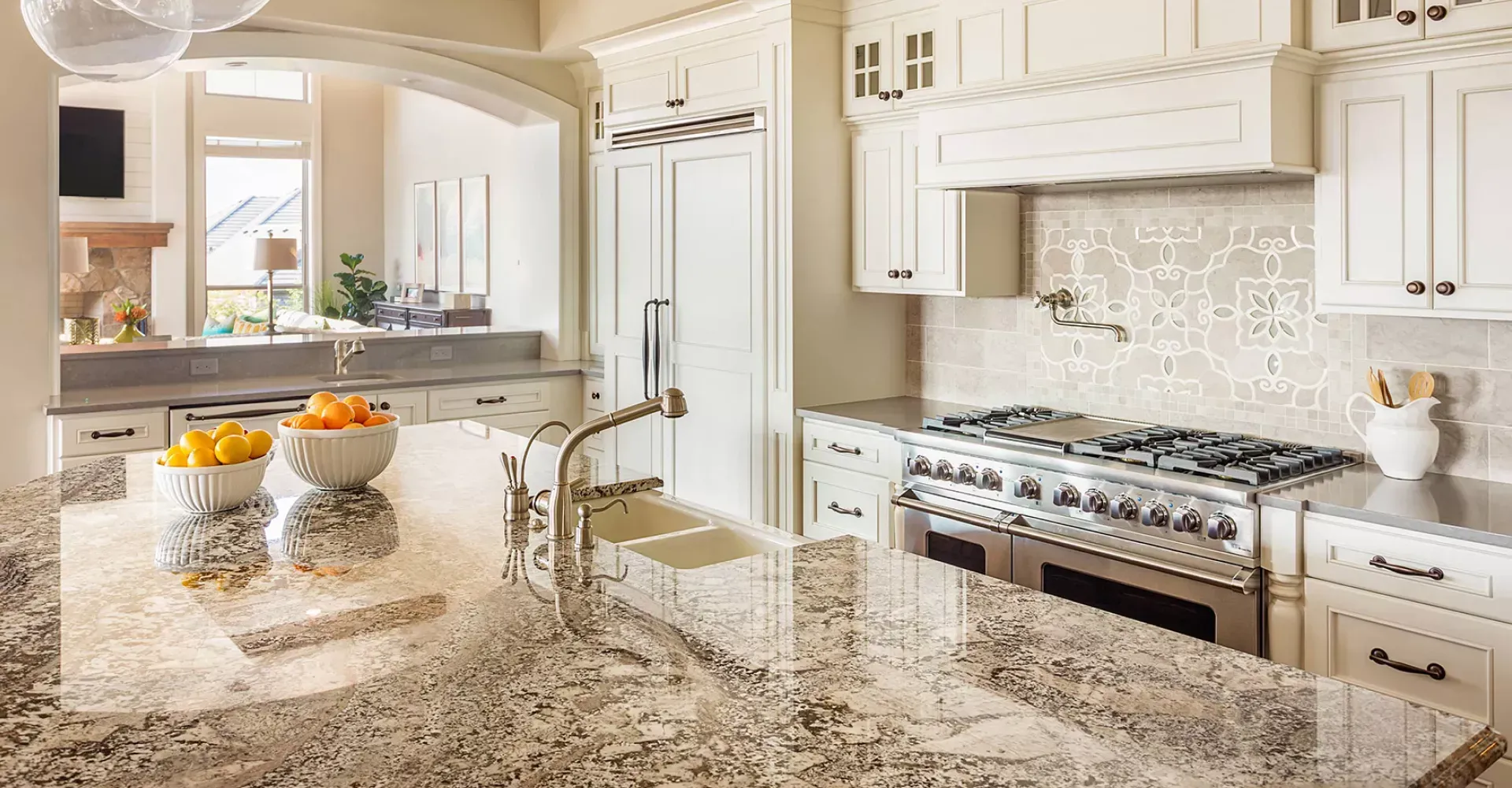 A kitchen with granite counter tops , stainless steel appliances , and white cabinets.