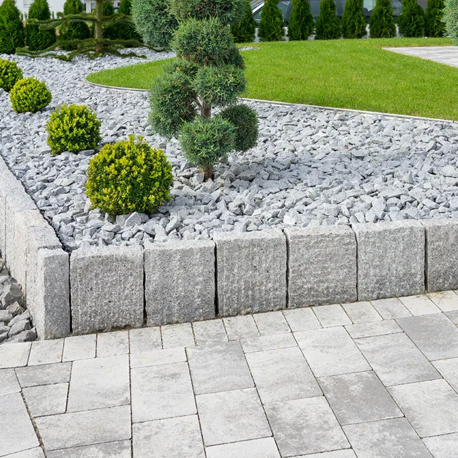 A garden with rocks , bushes and a tree in it