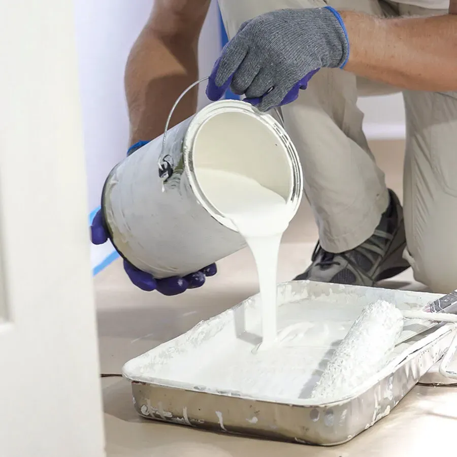 A person is pouring white paint into a tray