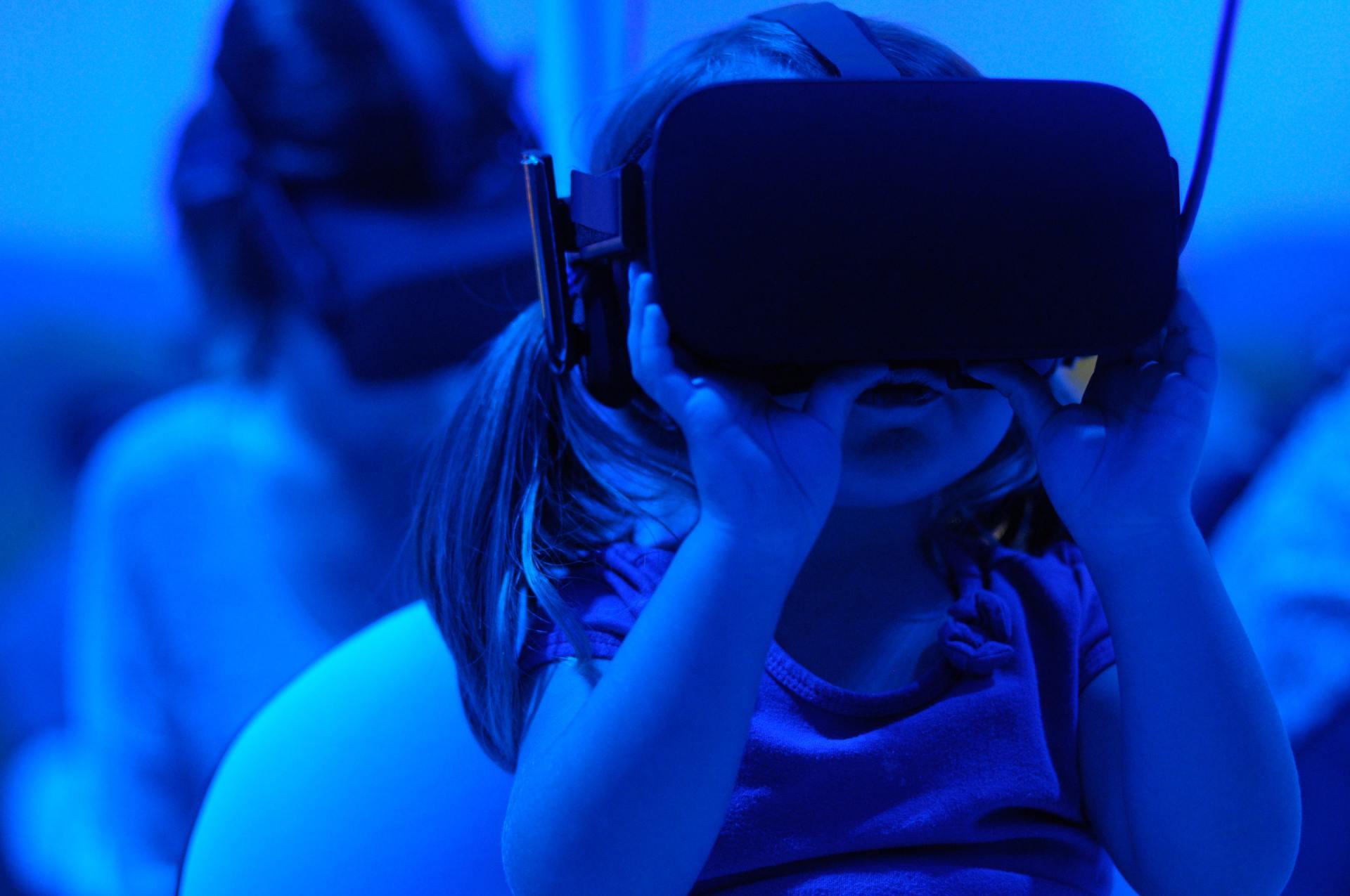 A little girl is wearing a virtual reality headset.