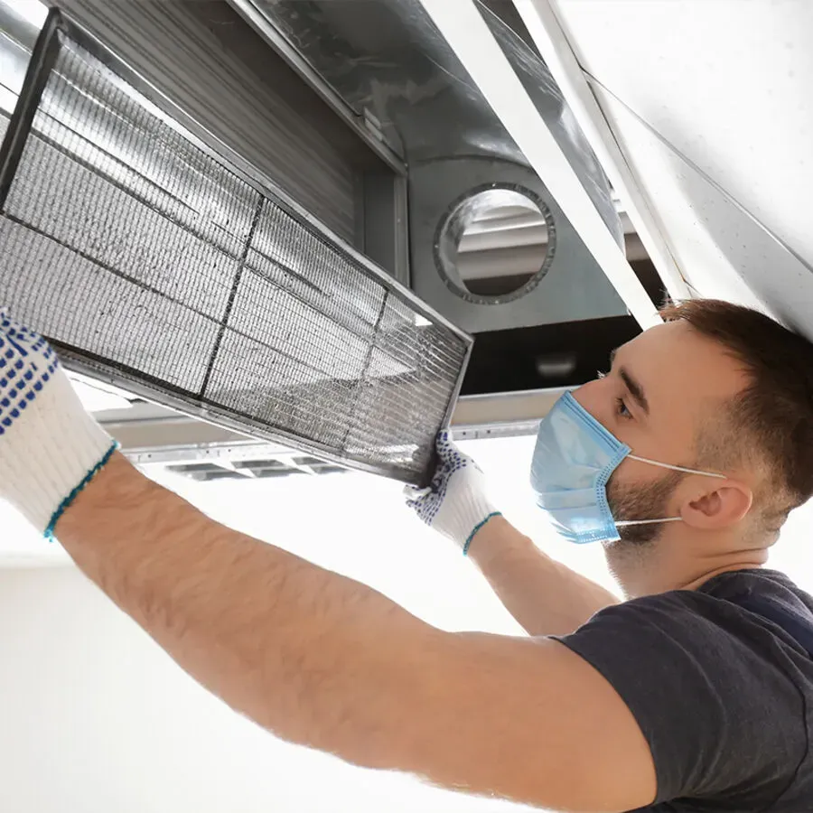 A man wearing a mask and gloves is working on an air conditioner