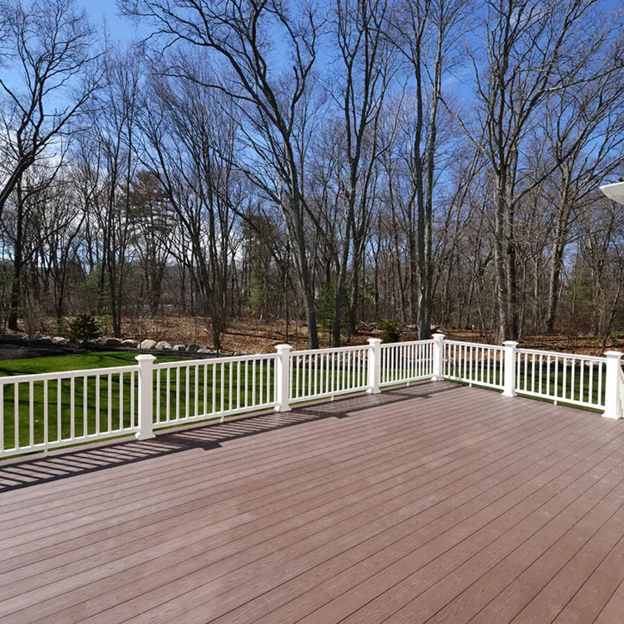 An empty deck with a white railing and trees in the background